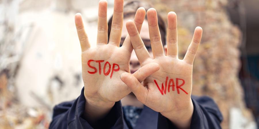 Woman's hands raised with slogan written in red Stop War
